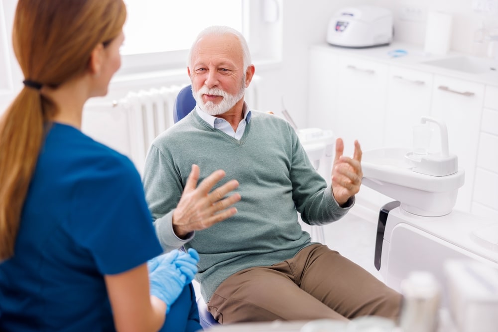 Dentiste qui discute avec son patient âgé